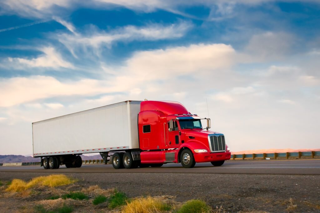 Red freight truck moving down a highway.